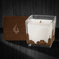 Image of a 3x3x3 soy candle featuring a mahogany scent, crackling wood wick, with a wood lid and an Boston skyline wrap design.