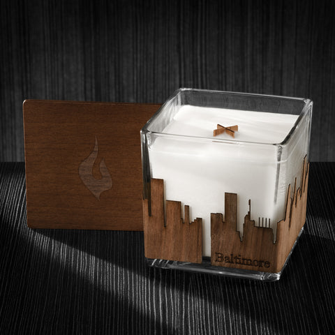 Image of a 4x4x4 soy candle featuring a mahogany scent, crackling wood wick, with a wood lid and an Baltimore skyline wrap design.