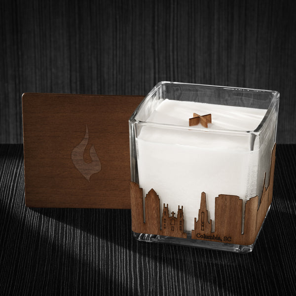 Image of a 4x4x4 soy candle featuring a mahogany scent, crackling wood wick, with a wood lid and a Columbia, SC  skyline wrap design.