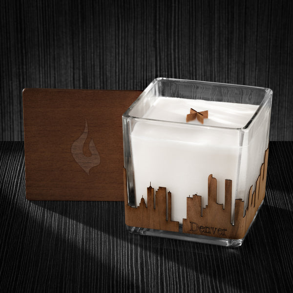 Image of a 4x4x4 soy candle featuring a mahogany scent, crackling wood wick, with a wood lid and a Denver skyline wrap design.