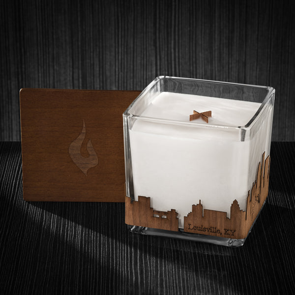Image of a 4x4x4 soy candle featuring a mahogany scent, crackling wood wick, with a wood lid and a Louisville, KY City skyline wrap design.