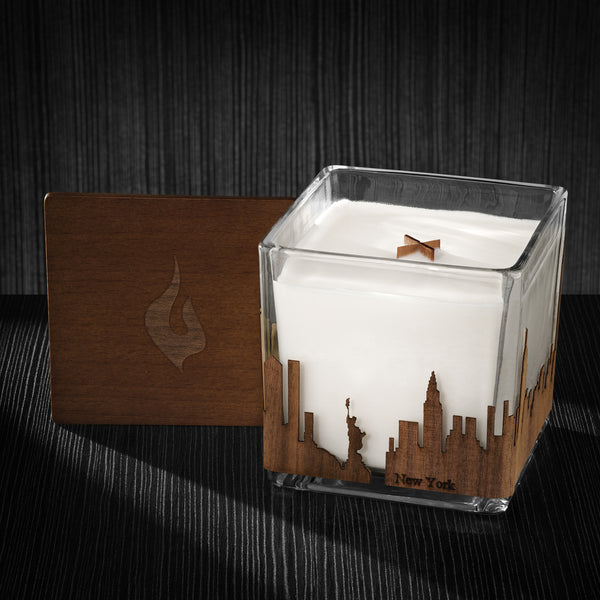 Image of a 4x4x4 soy candle featuring a mahogany scent, crackling wood wick, with a wood lid and a New York City skyline wrap design.