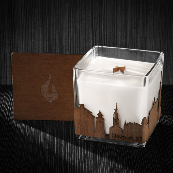 Image of a 4x4x4 soy candle featuring a mahogany scent, crackling wood wick, with a wood lid and a New Port City skyline wrap design.