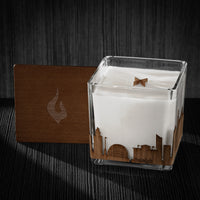 Image of a 4x4x4 soy candle featuring a mahogany scent, crackling wood wick, with a wood lid and a Raleigh City skyline wrap design.