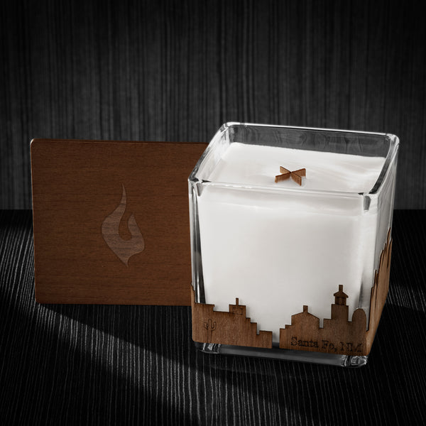 Image of a 4x4x4 soy candle featuring a mahogany scent, crackling wood wick, with a wood lid and a Santa Fe, NM skyline wrap design.