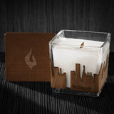 Image of a 3x3x3 soy candle featuring a mahogany scent, crackling wood wick, with a wood lid and an Baltimore skyline wrap design.