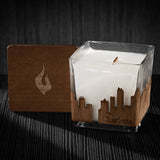 Image of a 3x3x3 soy candle featuring a mahogany scent, crackling wood wick, with a wood lid and an Charlotte skyline wrap design.