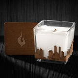 Image of a 3x3x3 soy candle featuring a mahogany scent, crackling wood wick, with a wood lid and a Denver skyline wrap design.