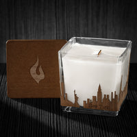 Image of a 3x3x3 soy candle featuring a mahogany scent, crackling wood wick, with a wood lid and a New York City skyline wrap design.