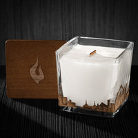Image of a 3x3x3 soy candle featuring a mahogany scent, crackling wood wick, with a wood lid and a Portland skyline wrap design.