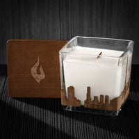 Image of a 3x3x3 soy candle featuring a mahogany scent, crackling wood wick, with a wood lid and a Toronto skyline wrap design.