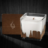 Image of a 3x3x3 soy candle featuring a mahogany scent, crackling wood wick, with a wood lid and a Columbia, SC  skyline wrap design.